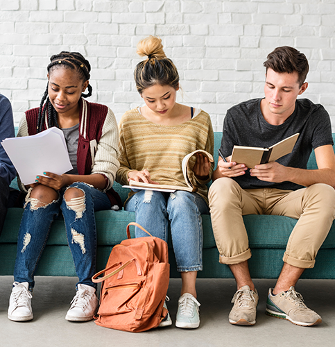 three students sitting on sofa reading books