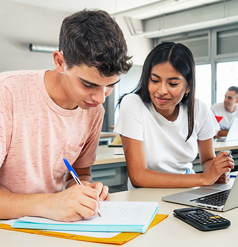 two students at a desk in classroom doing work together