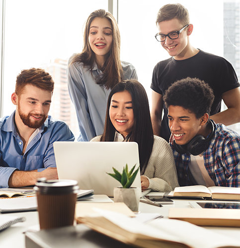 a group of five students in classroom gathered around a laptop