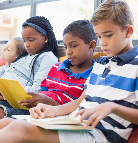 four young students casually reading in classroom setting