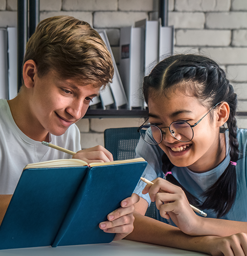 two students at a table with a book